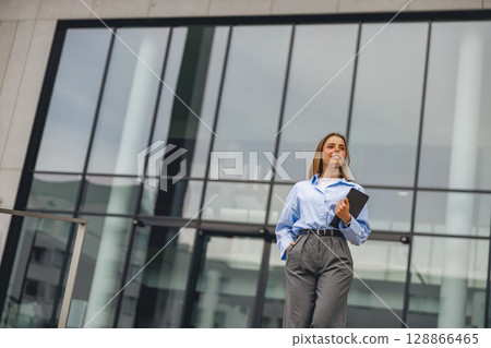A Professional Woman Strolling Through a Busy Business District with Confidence and Style 128866465