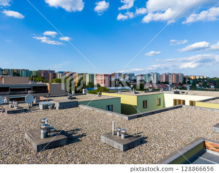 Aerial view of house flat roof on residental building. Modern architecture exterior. Air conditioning systems and ventilation structure. Residental building in background, sunny day Aerial view of house flat roof on residental building. Modern architecture exterior. Air conditioning systems and ventilation structure. Residental building in background, sunny day 128866656