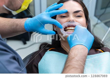 A Patient Undergoing Dental Examination: A Close-Up View of a Dental Procedure in Progress in a Modern Dental Clinic Environment with Professional Equipment and Care 128867069