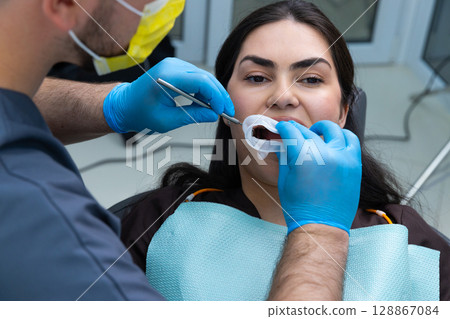 A Dentist Performing an Oral Examination with Precision and Care, Ensuring Patient Comfort with a Clean and Welcoming Environment Focused on Dental Health and Hygiene 128867084