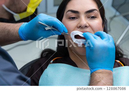 Patient Undergoing Dental Treatment with Professional Care in a Modern Clinic Environment at a Dental Office 128867086