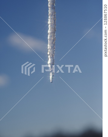 A long icicle hanging from a tree in the sky A long icicle hanging from a tree in the sky 128867510