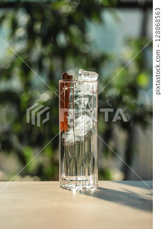 Crystal clear cocktail with ice cubes and cinnamon Crystal clear cocktail with ice cubes and cinnamon 128868563