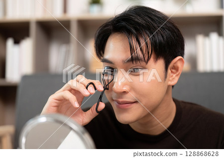Grooming Routine. Male using eyelash curler for a polished look. 128868628