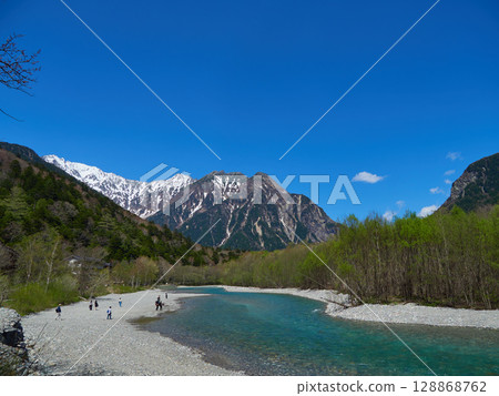 A view of tourists strolling along the banks of the Azusa River and the Hotaka mountain range in Kamikochi, a popular tourist spot in early summer 128868762