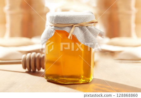 Honey Jar with a wood stick in a blurred background 128868860