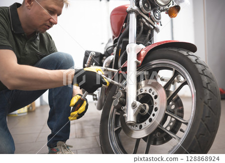 Man Repairs Classic Motorcycle In Garage 128868924