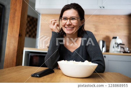 Girl Laughing And Eating Popcorn While Watching A Movie On Tv At Home Girl Laughing And Eating Popcorn While Watching A Movie On Tv At Home 128868955