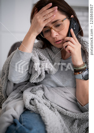 Young Woman Sick At Home And Calling On The Phone With A High Fever And Headache Young Woman Sick At Home And Calling On The Phone With A High Fever And Headache 128868987