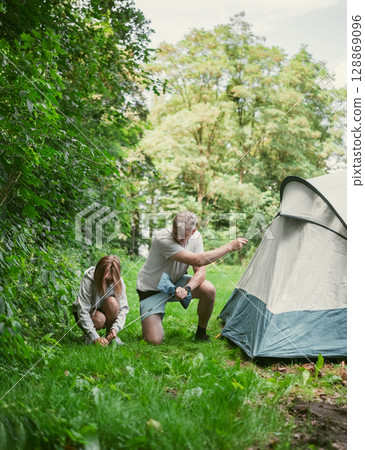 Father And Daughter Set Up A Tent At A Campground During Family Summer Camping Vacation 128869096