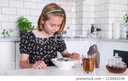 Little Girl Eating Dry Breakfast Cereal In The Kitchen For Breakfast 128869106