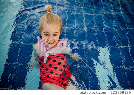 Little girl enjoying swim time in bright water with playful attitude on a sunny day 128869129