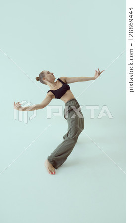 Fashionable model leaning backward in expressive open-arm pose with emotional intensity 128869443