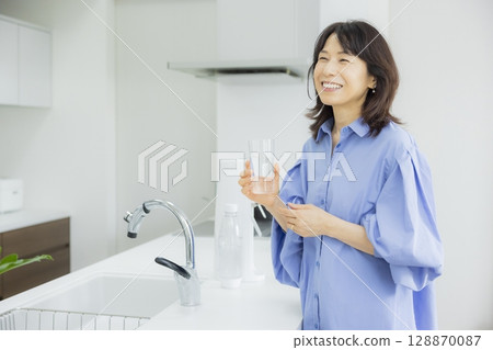 Woman drinking water in the kitchen 128870087