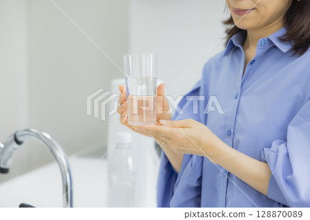 Woman drinking water in the kitchen Woman drinking water in the kitchen 128870089