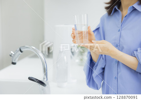 Woman drinking water in the kitchen Woman drinking water in the kitchen 128870091
