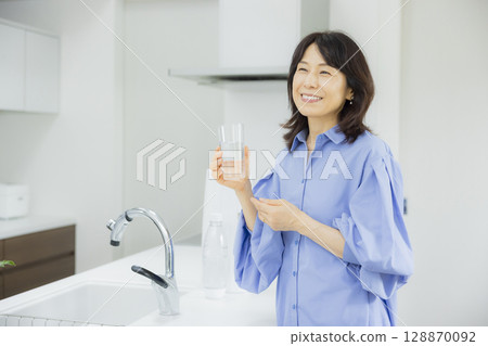 Woman drinking water in the kitchen 128870092