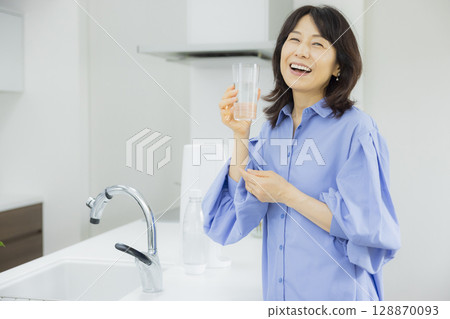 一個女人在廚房喝水 128870093