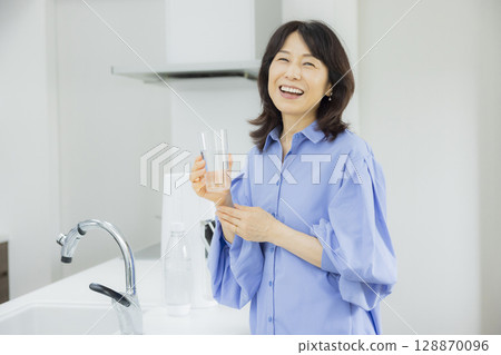 Woman drinking water in the kitchen Woman drinking water in the kitchen 128870096