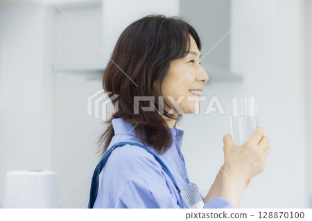 Woman drinking water in the kitchen 128870100