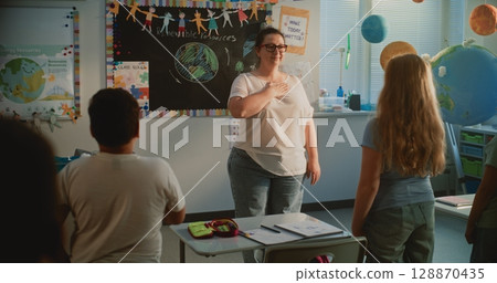 Primary School Children Performing the Country's National Anthem with Female Teacher Before Lesson 128870435