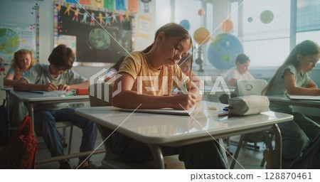 Elementary School Students Sitting at Desks, Writing Exam or Lecture in Modern Classroom 128870461