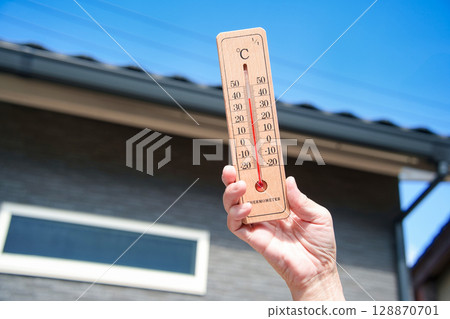 極熱的一天:一名婦女手持溫度計,顯示家附近的室外溫度為 39°C 極熱的一天:一名婦女手持溫度計,顯示家附近的室外溫度為 39°C 128870701