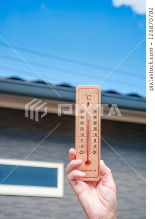 極熱的一天：一名婦女手持溫度計，顯示家附近的室外溫度為 39°C 128870702