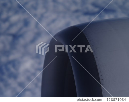 Jet engine is shown in a close up with a blue sky background Jet engine is shown in a close up with a blue sky background 128871084