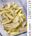 Closeup of pickled ambarella fruit, also called golden apples, in a glass container. 128871119