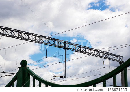 A picturesque bridge stands against a bright blue sky and clouds 128871535