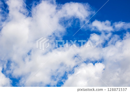 There is a beautiful blue sky adorned with fluffy white clouds in it 128871537
