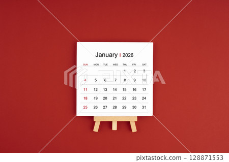 Calendar page for January 2026 with wood easel on a dark red background. Calendar page for January 2026 with wood easel on a dark red background. 128871553
