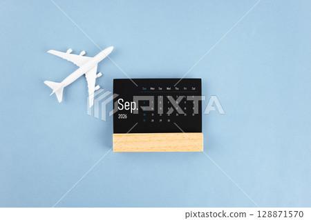 September 2026 black wooden calendar and airplane toy on blue color background. 128871570