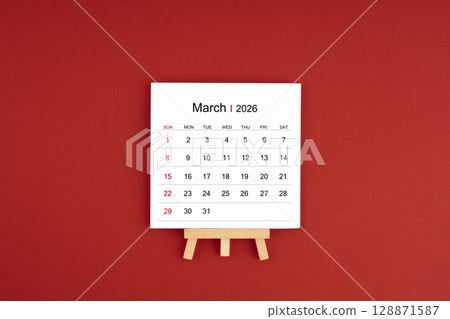 Calendar page for March 2026 with wood easel on a dark red background. Calendar page for March 2026 with wood easel on a dark red background. 128871587