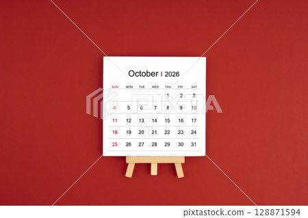 Calendar page for October 2026 with wood easel on a dark red background. 128871594