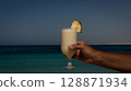 man drinking glass of pina colada on beach 128871934