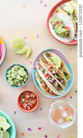 Cinco de Mayo tacos presented with traditional Mexican garnishes, background 128872030