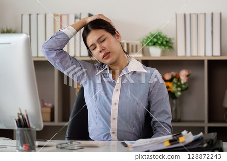 Office Syndrome: Woman stretching neck to relieve tension at her desk 128872243
