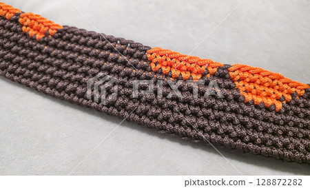 The bottom of the bag is crocheted from brown and orange cord. On a wooden base. 128872282