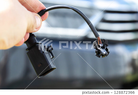 Black car outside air temperature gauge against car headlight background, industry 128872366