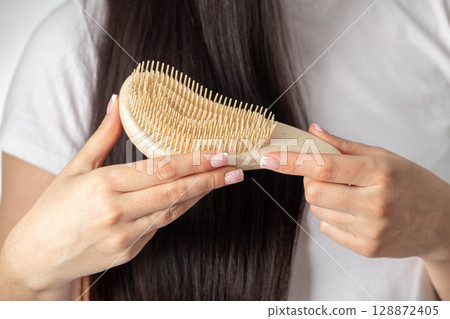 Girl holding massage comb on black hair background. Wet and tangled hair care, close-up. Hair care Girl holding massage comb on black hair background. Wet and tangled hair care, close-up. Hair care 128872405