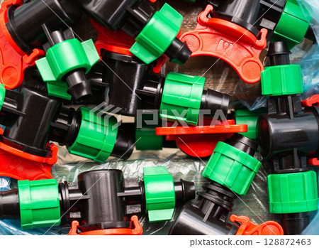Multicolored plastic taps for assembling drip irrigation at the dacha, close-up 128872463