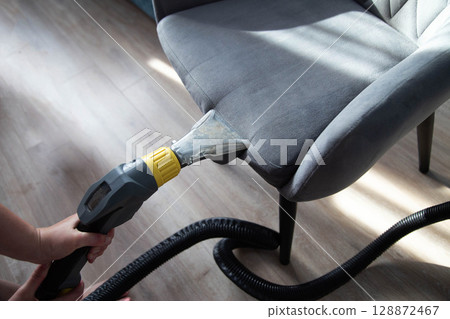Services for washing and cleaning upholstered furniture with a vacuum cleaner. Cleaning dirty gray chairs in the apartment, industry 128872467