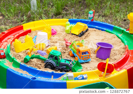 Modern round colorful children's sandbox with toys and molds, close-up 128872767