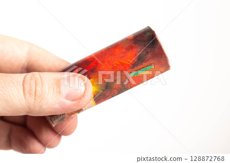 Firecracker with a wick in hand on a white background, isolate, close-up. Copy space for text. Fireworks Explosion Safety 128872768