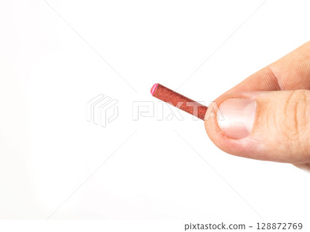Firecracker with a wick in hand on a white background, isolate, close-up. Copy space for text. Fireworks Explosion Safety 128872769