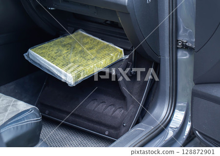 Replacement of a modern new anti-allergenic and antibacterial cabin filter in a car, close-up 128872901