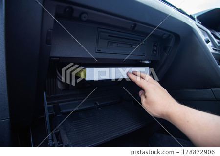 Mechanic's hand replacing old car cabin filter with new clean filter, close-up, industry, antibacterial 128872906