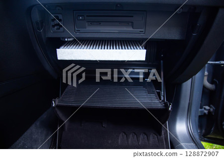 Replacement of a modern new anti-allergenic and antibacterial cabin filter in a car, close-up 128872907